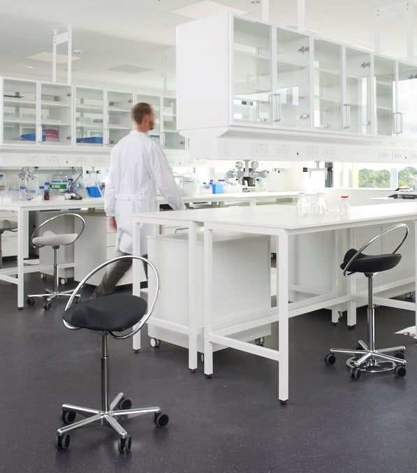 Laborant i laboratorie. Der står InCharge stole som han skal bruge når han sidder og arbejder.